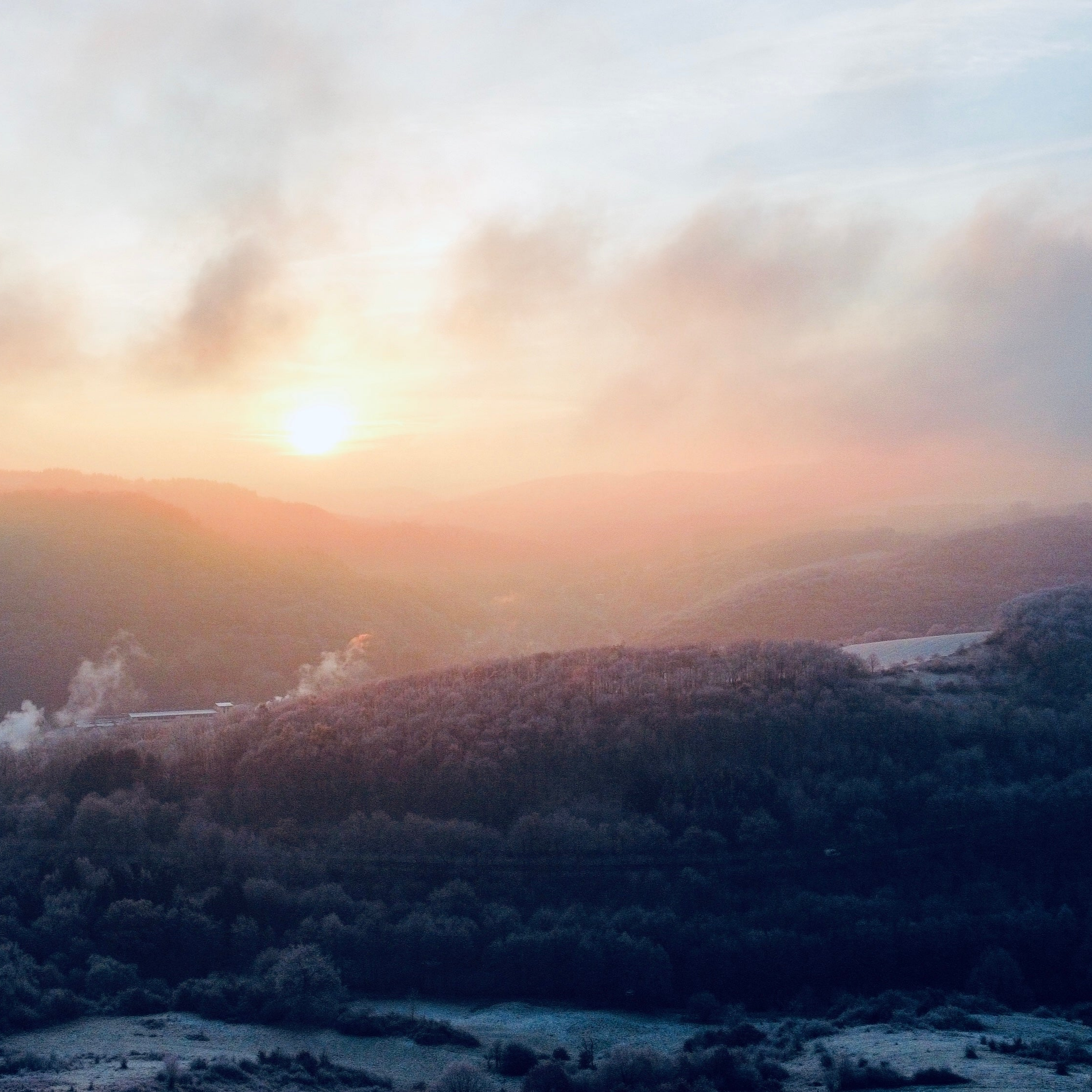 Panoramaaufnahme des Nordpfälzer Berglandes aus der Vogelperspektive, erfasst mit einer Drohne während des Sonnenaufgangs, die die vereiste Landschaft in warmes Licht taucht.