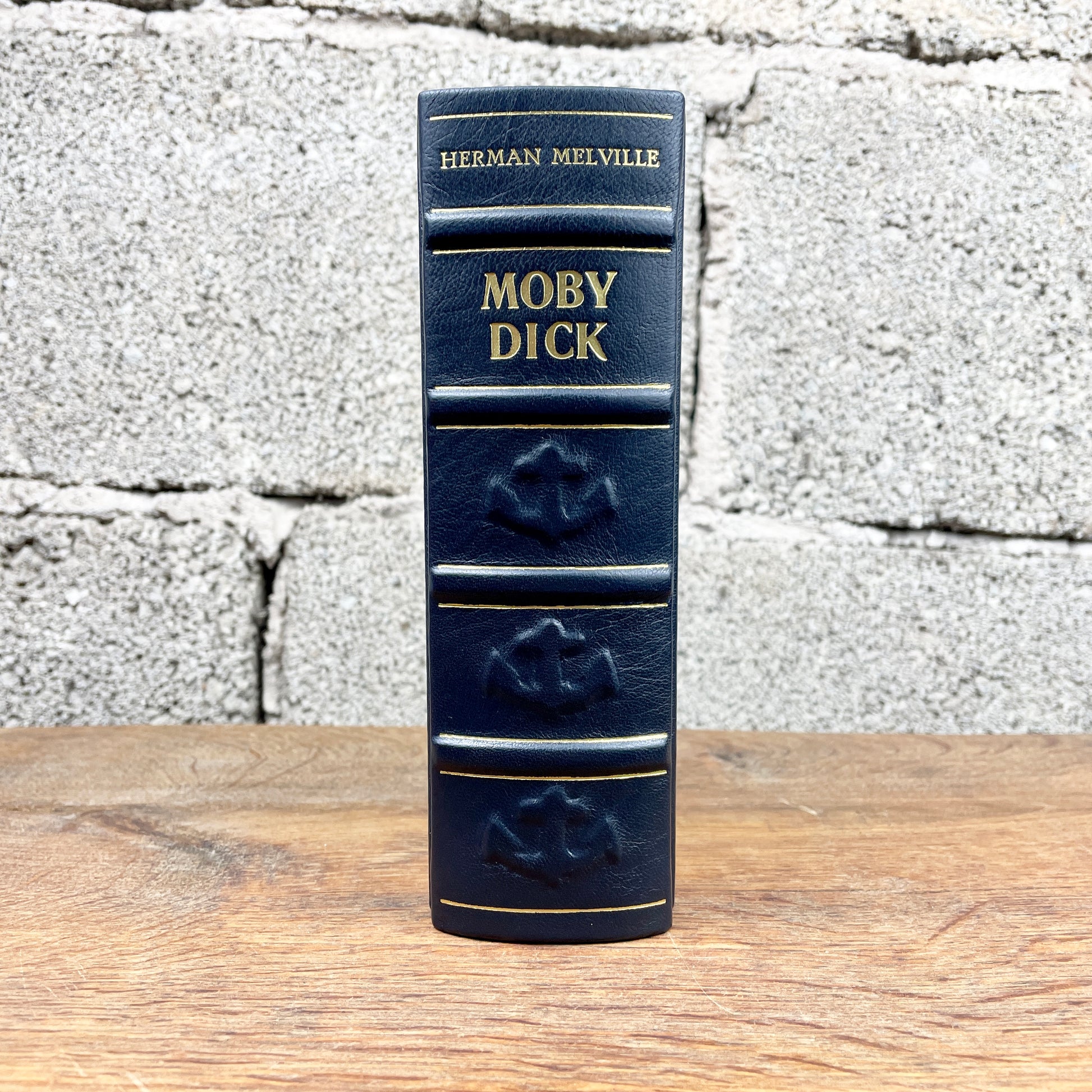 Handgefertigte Ledereinband-Ausgabe von Moby Dick von Herman Melville in dunkelblauem Leder mit goldenen Prägungen, Anker- und Steuerrad-Reliefs sowie stilisierter Lederintarsie des weißen Wals, hergestellt von annabuchwunder.